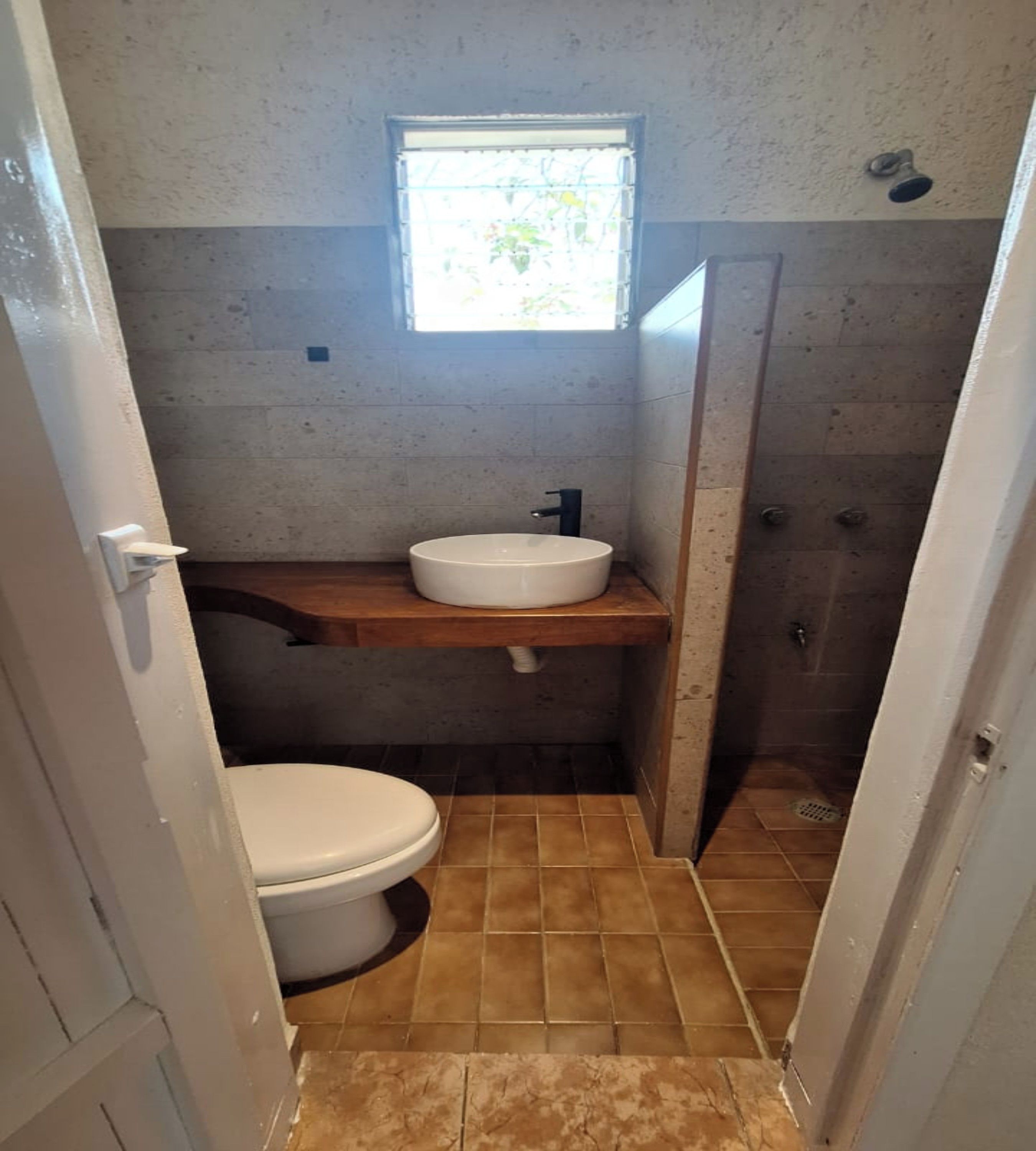 A small bathroom with a toilet, a sink, and a shower.