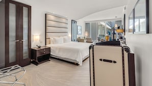 Ett modernt hotellrum med en stor säng, ett skrivbord, en stol och en resväska.