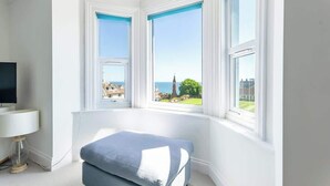 Une chambre avec une baie vitrée, un lit, une télévision et une lampe.