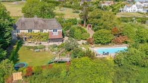 Una casa con un patio trasero amplio, una piscina y un jardín.