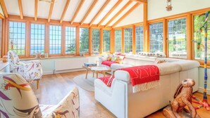 Una sala de estar acogedora con un sofá blanco, un sillón estampado y piso de madera.