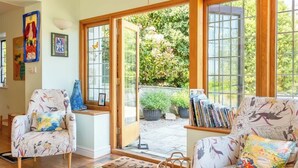 Una sala de estar acogedora con dos sillones estampados, una mesita de centro y una estantería llena de libros.