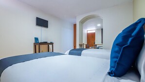 A hotel room with two beds, a desk with a computer, a flat-screen TV, and a mirror. - Hotel Mosna (Arequipa)