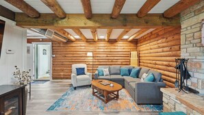 A log cabin interior with a sofa set, a coffee table, and a fireplace.