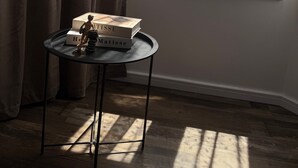 Ein Zimmer mit Fenster, Tisch und Büchern, sowie Vorhänge.