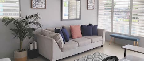 A living room with a sofa, a coffee table, a bench, and a potted plant.