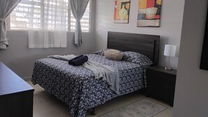 A bedroom with a bed, a nightstand, a lamp, and two wall art pieces.