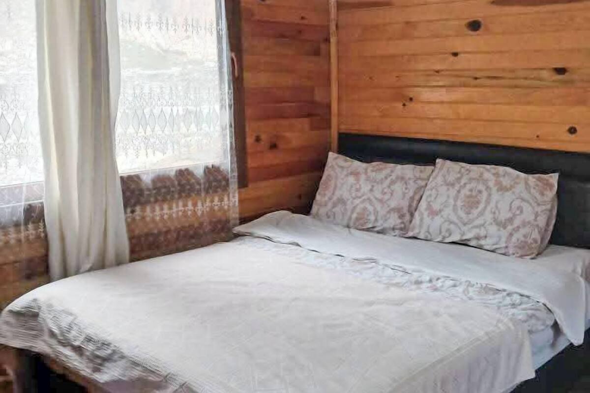 Une pièce aux murs lambrissés, avec un lit, des rideaux et un sol à motifs.