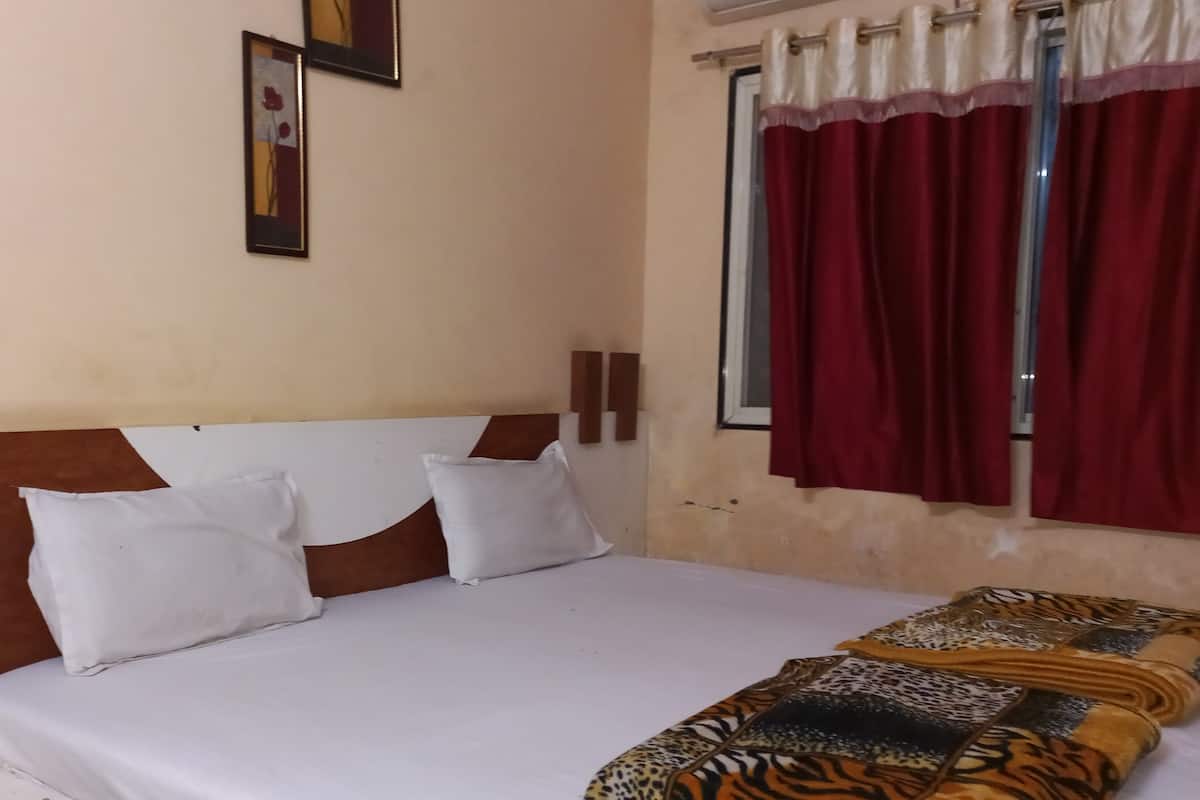 A bed with white bedding, a patterned blanket, and a headboard with two white pillows.