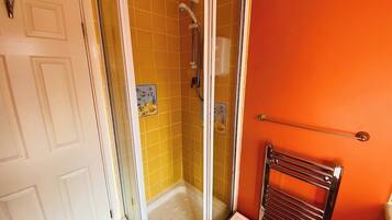 Un baño con ducha, una puerta blanca y un perchero para toallas.