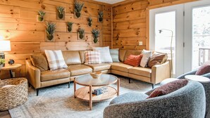 Ein gemütliches Wohnzimmer mit einem Ecksofa, einem runden Couchtisch und einer Wandpflanzenanzeige.