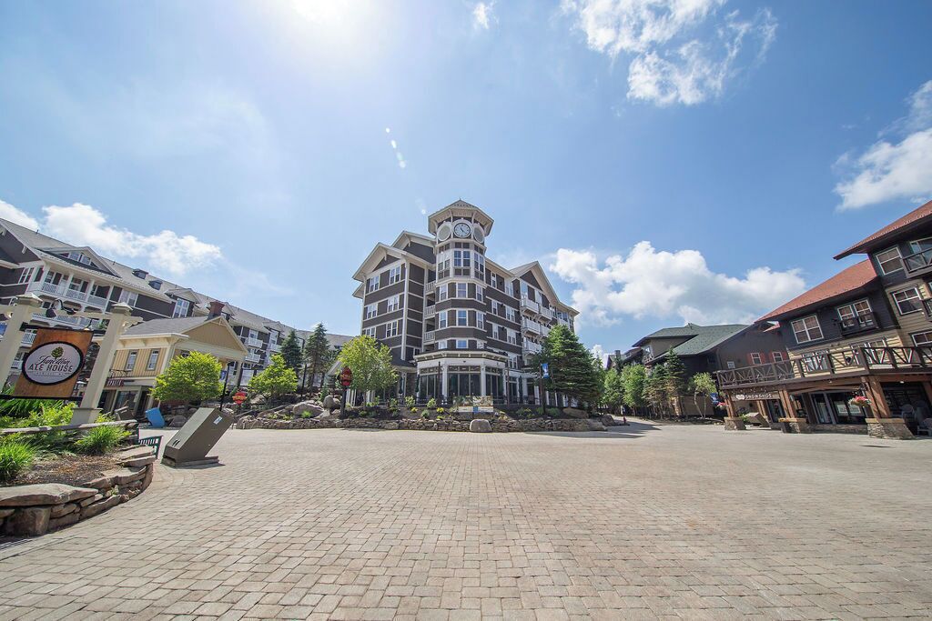 A multi-story building with a clock tower, surrounded by a paved plaza with trees and a sign for 'The Ale House'.