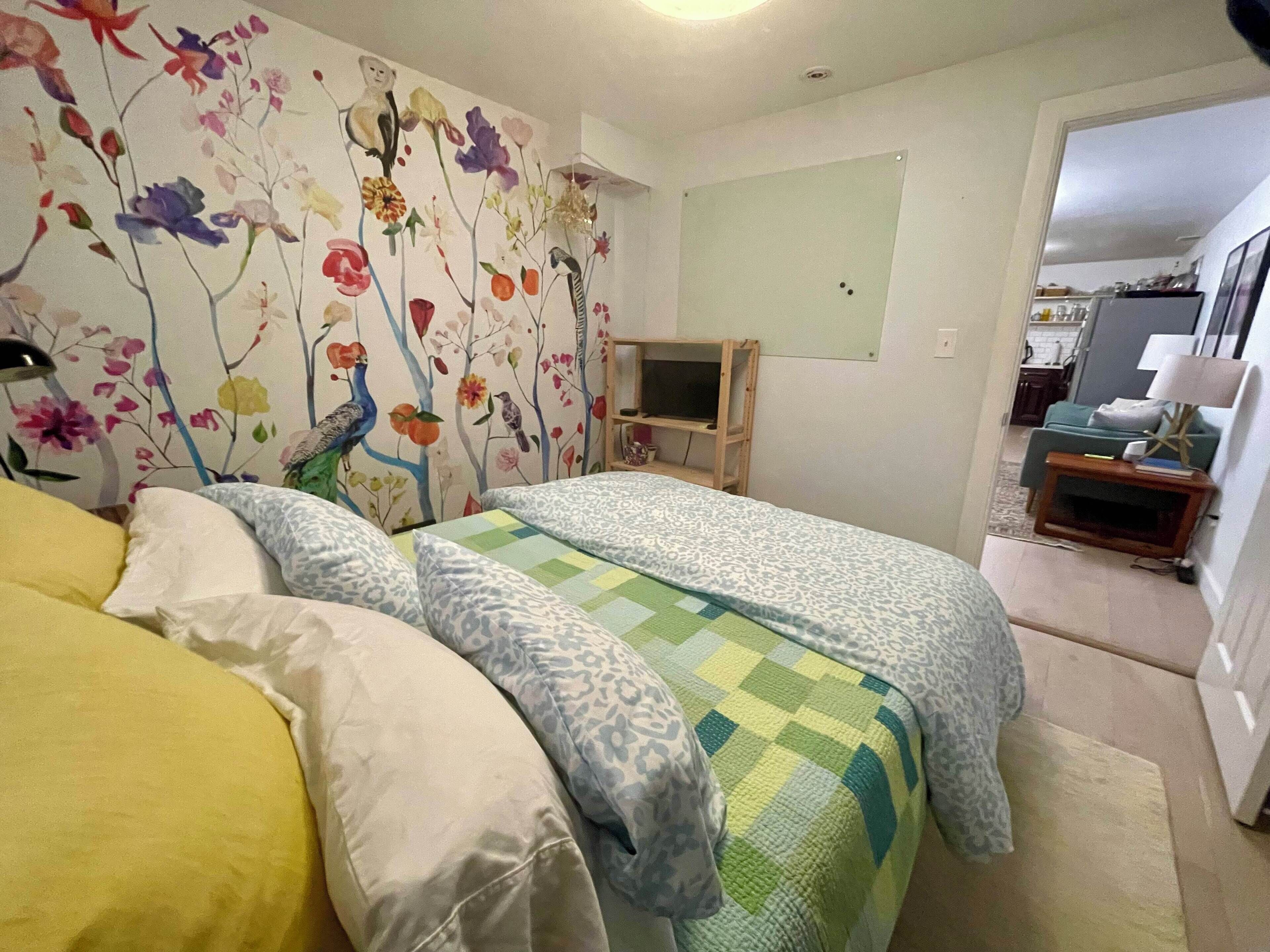A bedroom with two beds, a TV, and a floral wall mural.
