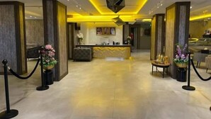 Un hall d’hôtel comprenant un comptoir d’accueil, un espace salon et des plantes décoratives.