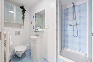 Une salle de bain équipée de toilettes, d’un lavabo, d’un miroir et d’une douche.