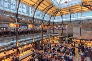 Un vaste marché couvert à plusieurs niveaux, avec des murs en briques apparentes et une grande variété de boutiques et de restaurants.