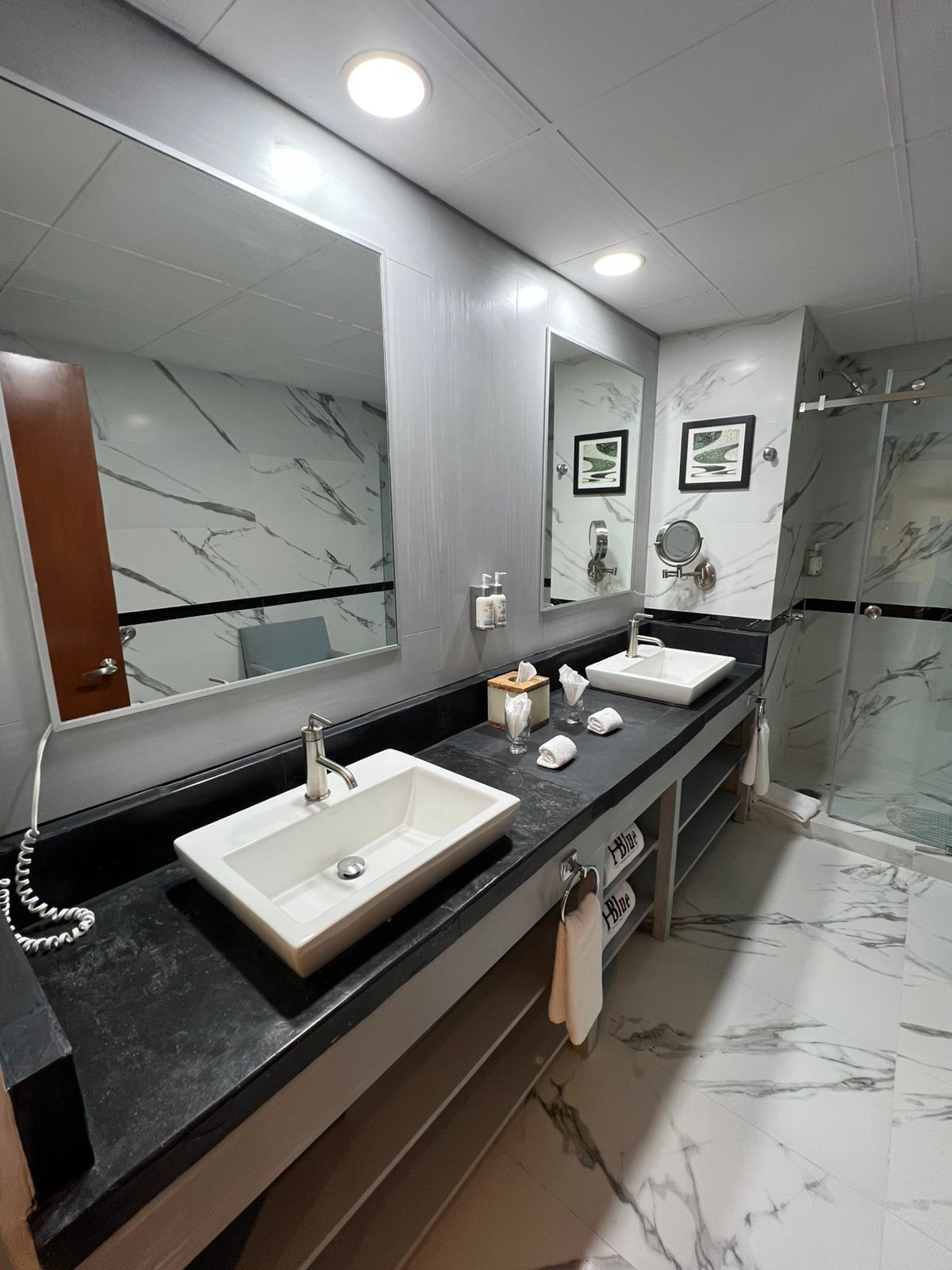 Un baño moderno con dos lavamanos, un espejo grande y una zona de ducha.