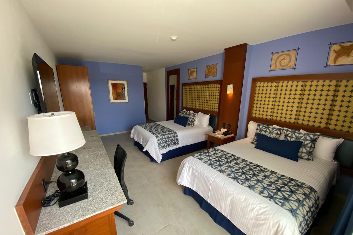 Une chambre d’hôtel avec deux lits, un bureau, une chaise, une lampe et un téléphone.