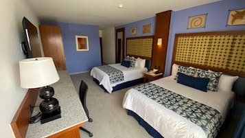 Habitación de hotel con dos camas, un escritorio, una silla, una lámpara y un teléfono.
