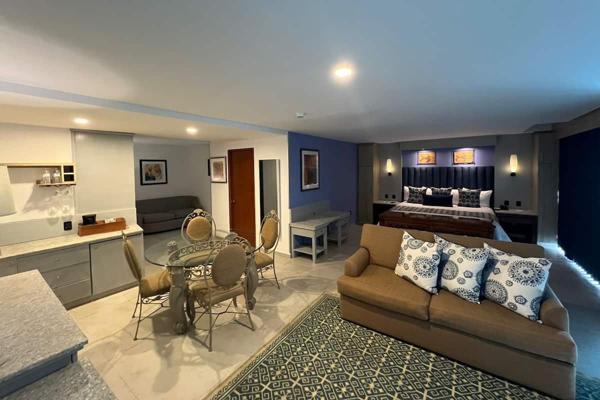 Une chambre d’hôtel moderne comprenant un coin repas, un canapé, un lit et une kitchenette.