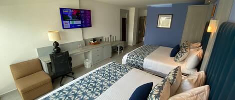 A hotel room with two beds, a desk, a chair, and a TV mounted on the wall.