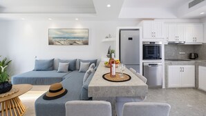 A modern living space with a sofa, dining table, and kitchen area. - calmare collection hotel (Naxos)