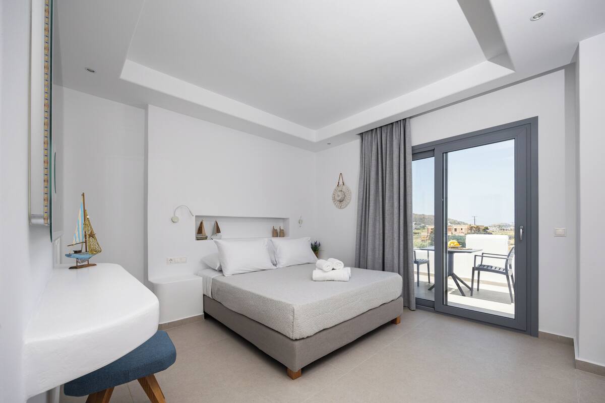Un dormitorio moderno con cama, un escritorio pequeño y un balcón.