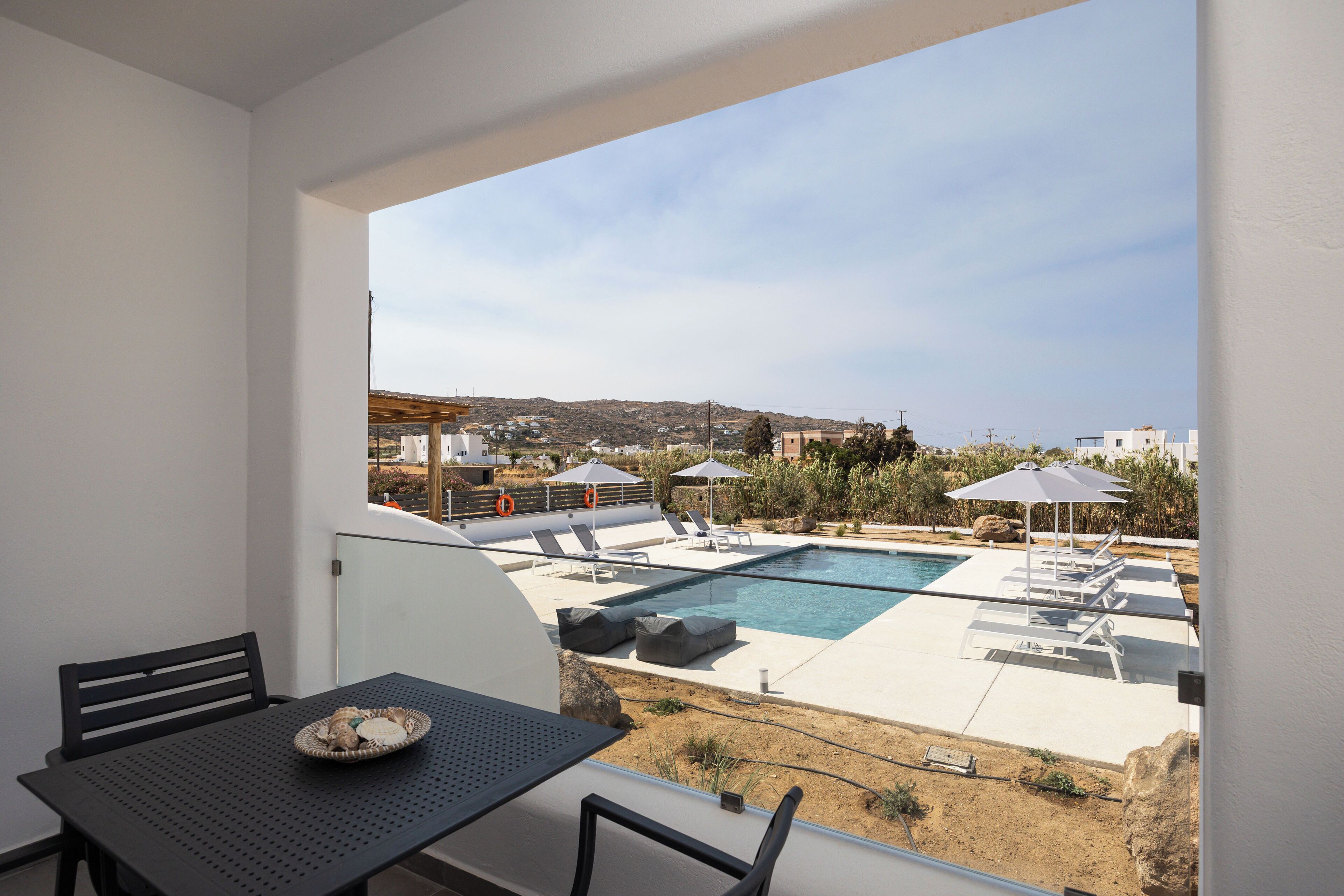 Un balcone con piscina, sedie a sdraio e un tavolo con un piatto di cibo.