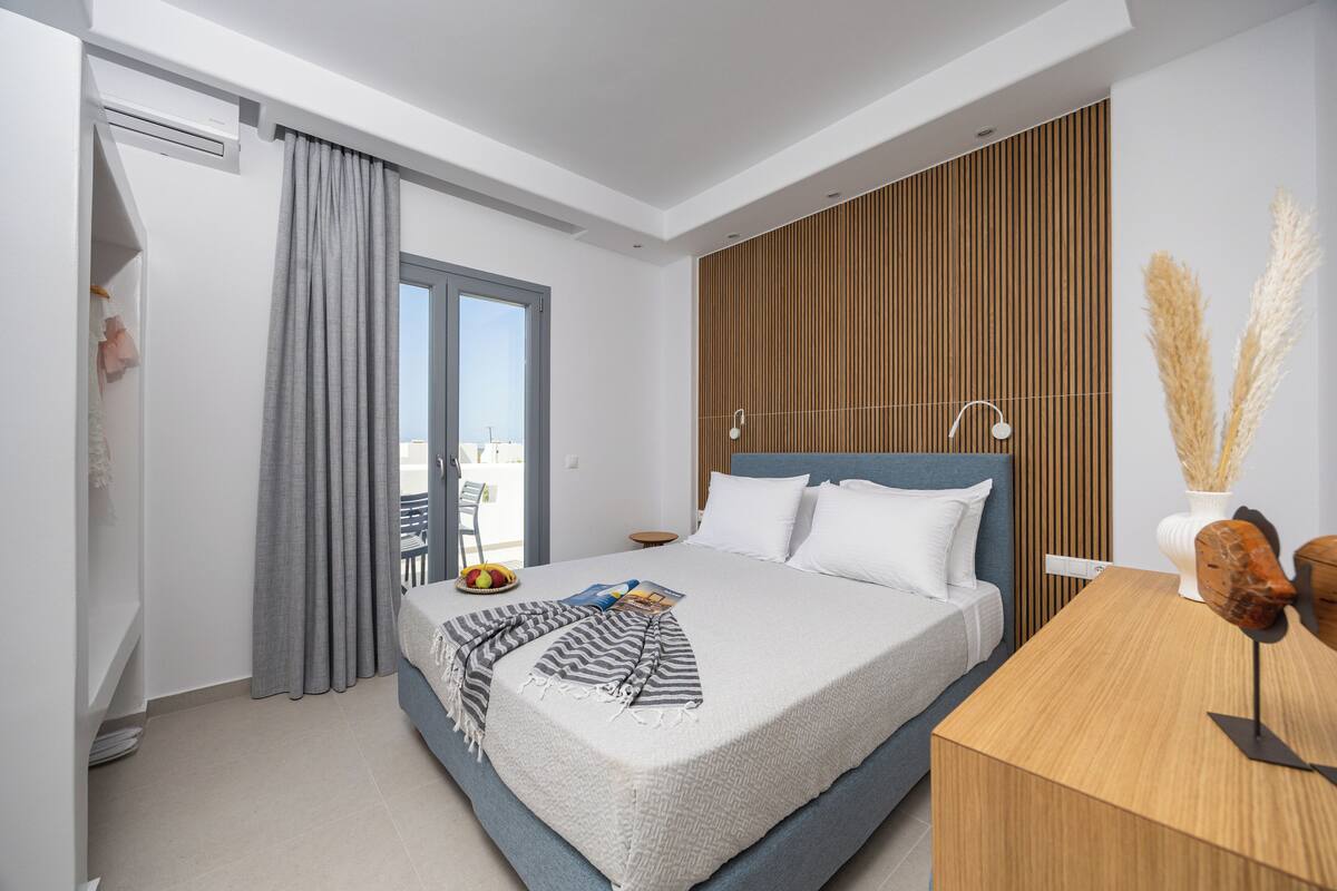 Un dormitorio moderno con una cama grande, un cabecero de madera, una mesita de noche y vistas al exterior.