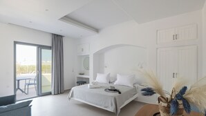 A modern bedroom with a large bed, a small table, and a view of the outside balcony. - calmare collection hotel (Naxos)