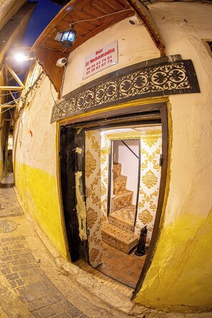 A narrow street with a building entrance featuring a sign with contact information. - Dar Mohamadia  (Fes)