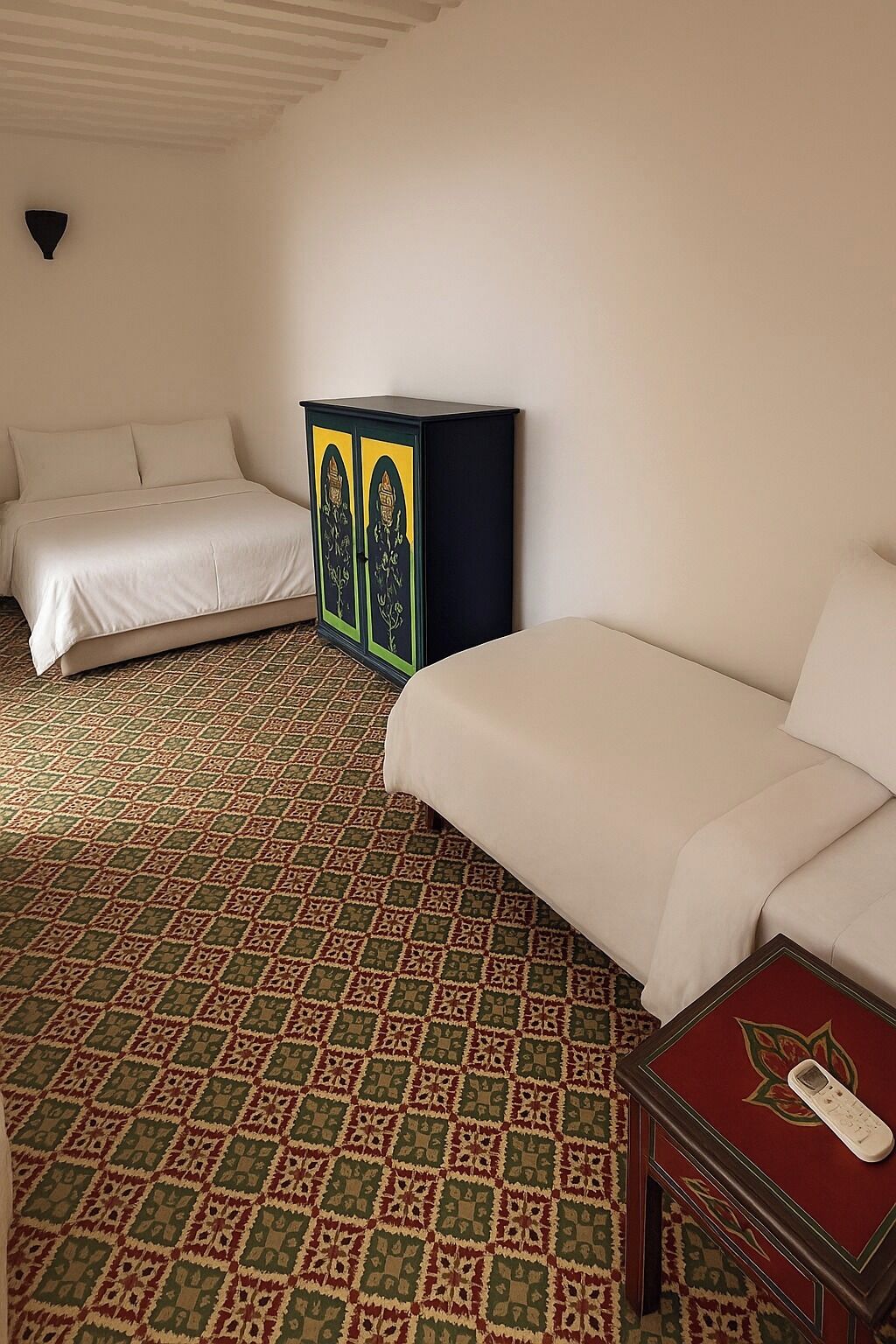 A hotel room with a patterned carpet, a bed, a sofa, and a cabinet with decorative panels.