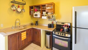 A kitchen with wooden cabinets, a stainless steel sink, a microwave, a stove, and a refrigerator. - 2-bedroom apartment in charming Cuidad Colon with WiFi. (Cuidad Colon)