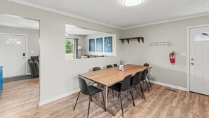 Ein Essbereich mit einem langen Holztisch, schwarzen Stühlen und einer weißen Decke.