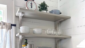 A kitchen with white wooden shelves holding bowls, glasses, and a coffee maker. - NEW! Pine Cottage - Walk to Everything in Downtown Bryson City! (Bryson City)