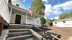A stone staircase leading to a porch with an American flag. - NEW! Pine Cottage - Walk to Everything in Downtown Bryson City! (Bryson City)