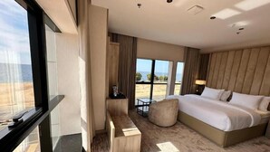Une chambre d’hôtel avec un grand lit, un bureau, une chaise et une vue sur la plage.