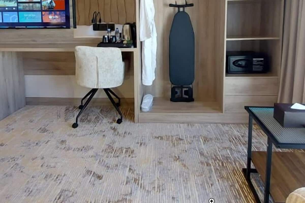 A compact hotel room with a bed, a TV mounted on the wall, a desk with a chair, and a built-in wardrobe.