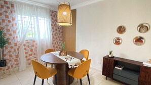 A dining area with a round table, yellow chairs, a hanging light fixture, and a wooden sideboard. - Cozy apartment with style and swimming pool (Villa Hermosa)
