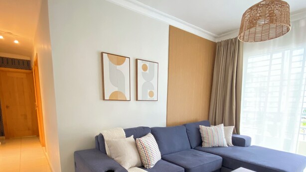 A modern living room with a sectional sofa, a coffee table, and a hanging light fixture. - Cozy apartment with style and swimming pool (Villa Hermosa)
