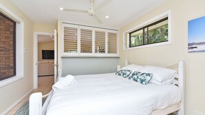 A bedroom with a bed, a ceiling fan, a window with blinds, and a view of the outdoors.