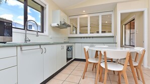 A modern kitchen with white cabinets, a built-in oven, and a dining area with a round table and wooden chairs.