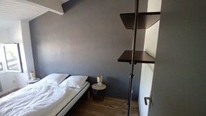 Een slaapkamer met een bed, nachtkastje, lamp en een staande vloerlamp.