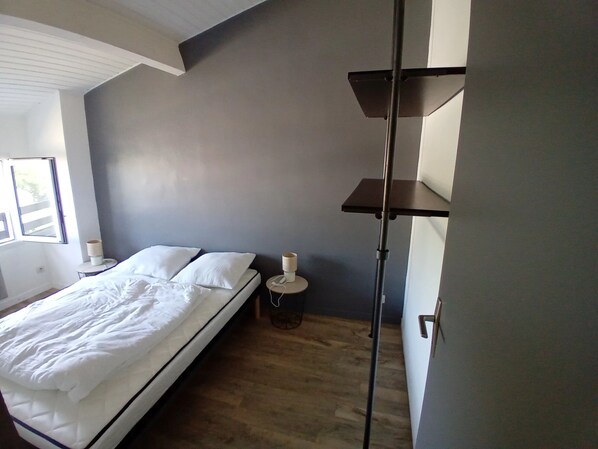 Quarto com cama, mesa de cabeceira, abajur e um candeeiro de chão.
