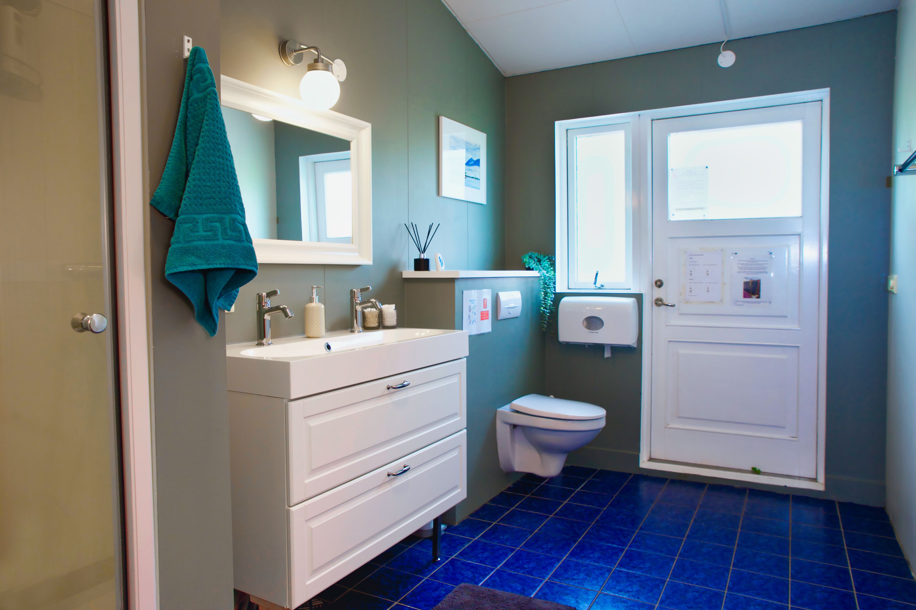 A bathroom with a white vanity, a sink, a mirror, a toilet, and a blue-tiled floor.