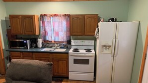 Una cocina compacta con armarios de madera, un microondas, una estufa y un refrigerador.