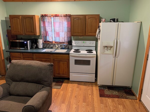 A compact kitchen with wooden cabinets, a microwave, a stove, and a refrigerator.