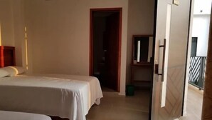 Een hotelkamer met twee bedden, een badkamer en een balkon.