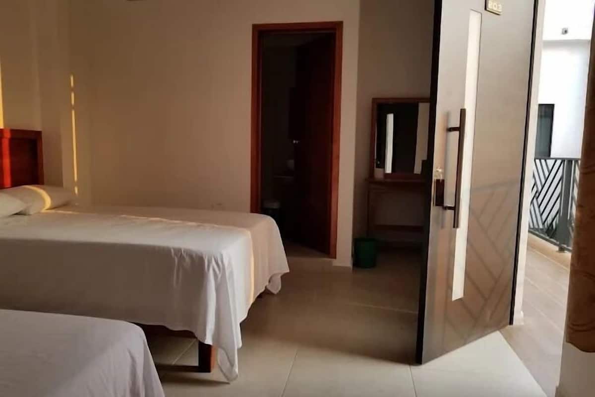 Une chambre d’hôtel avec deux lits, une salle de bain et un balcon.