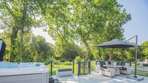 Une terrasse dotée d’un jacuzzi, de mobilier d’extérieur et d’une pergola.